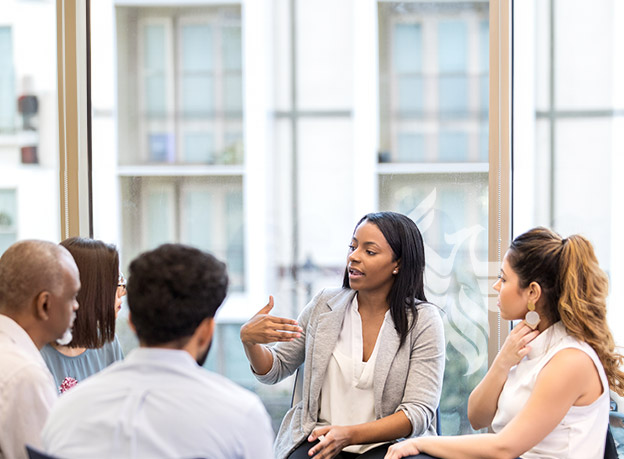 Five people are discussing a topic while seated in a circle.
